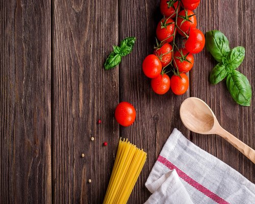 Italian fresh ingredients including tomatoes, basil, and pasta on a table
